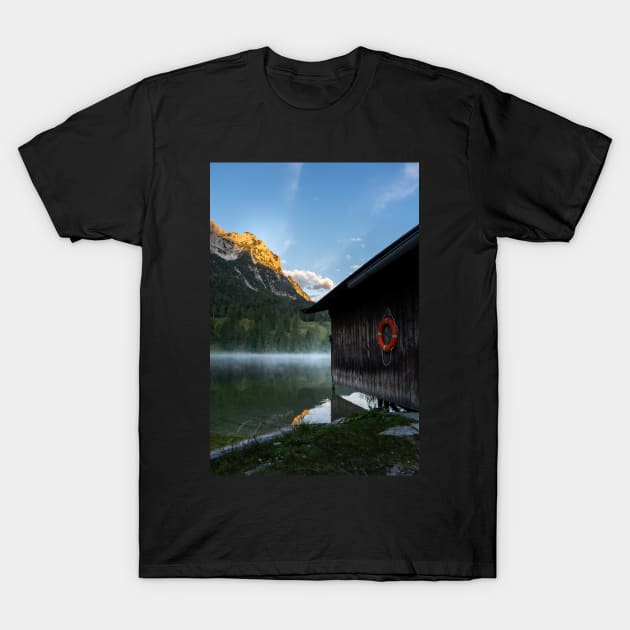Boathouse with lifesaver Portrait. Amazing shot of a wooden house in the Ferchensee lake in Bavaria, Germany, in front of a mountain belonging to the Alps. Scenic foggy morning scenery at sunrise. T-Shirt by EviRadauscher